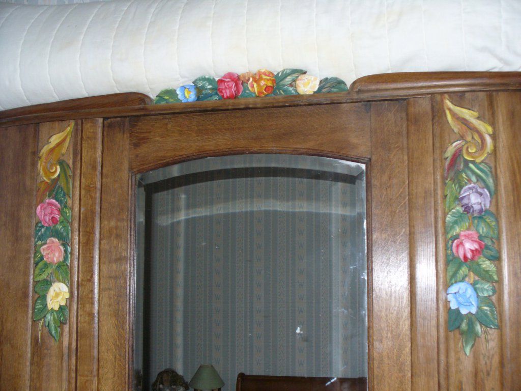 L'armoire en chêne style des années 50, est cirée, les guirlandes de fleurs sont peintes avec une peinture à l'huile de couleur.