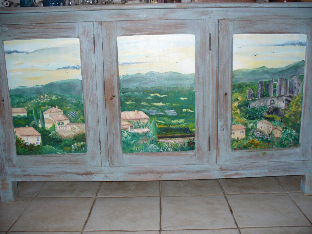 Sur ce meuble, j'ai appliqué une patine identique au précédent meuble, sur les panneaux des portes, j'y ai peint un trompe l'oeil 'paysage de Provence', en peinture acrylique . J'ai mis un vernis en finition
