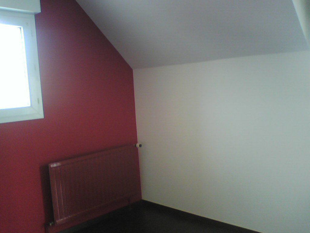 Le papier peint rouge sombre autours de la fenêtre assortis au papier peint  blanc cassé du reste des murs donne une certaine classe à la pièce sous comble, j'ai peint le radiateur d'un ton plus sombre que la tapisserie.