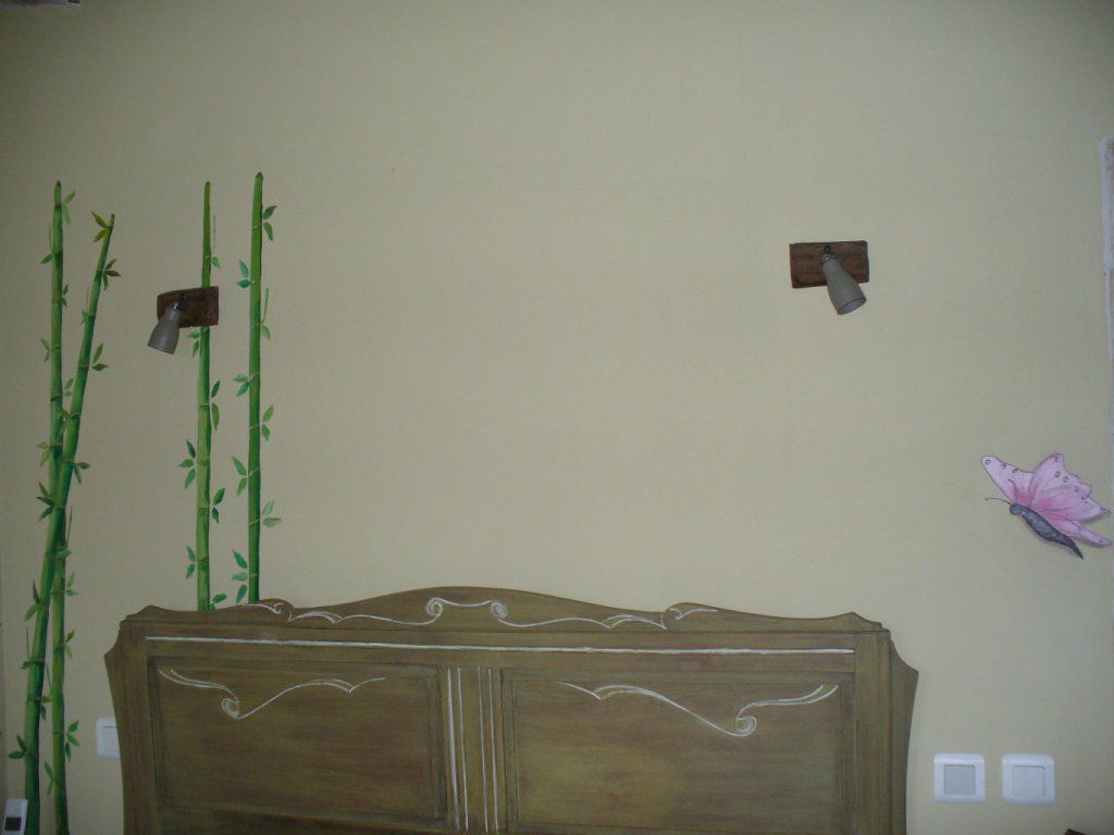 Après préparation, une peinture à la chaux a été appliqué, en harmonie avec le lit année 50, cérusé vert olive 
Un papillon et des bambous en trompe l'oeil, sont placés en tête de lit et casse l'uniformité du mur