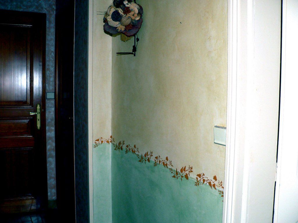 Pour donner un peu de lumière dans le couloir d'une maison année 50, une peinture acrylique clair a été appliqué sur les murs, après préparation. Un effet nuageux a été obtenu avec de la cire teinté . Une frise sépare les deux parties de deux teintes.