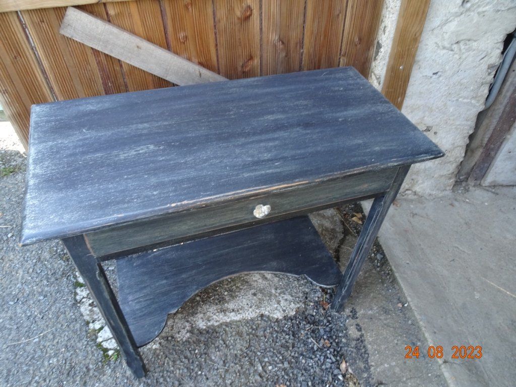 La table a été décapé puis peinte avec une peinture acrylique gris moyen, recouverte d'une peinture noire, poncé pour laisser réapparaitre la peinture grise en dessous.
Une finition avec une patine grise a été posé pour faire ressortir le dessous.