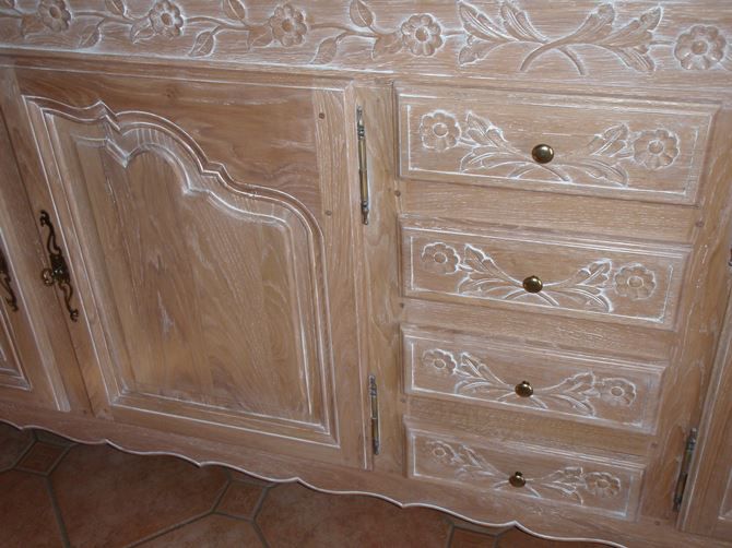 Après décapage et ponçage, une céruse blanche a été appliqué, le meuble a été poncé pour découvrir le fil du bois mais on laisse les moulures et sculptures cérusé pour faire ressortir les dessins